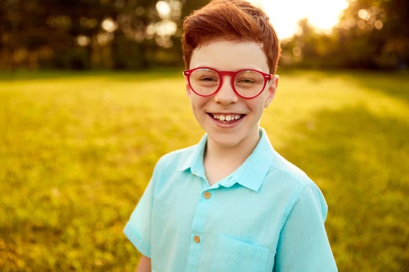 Happy confident youg boy wearing bright red stylish glasses